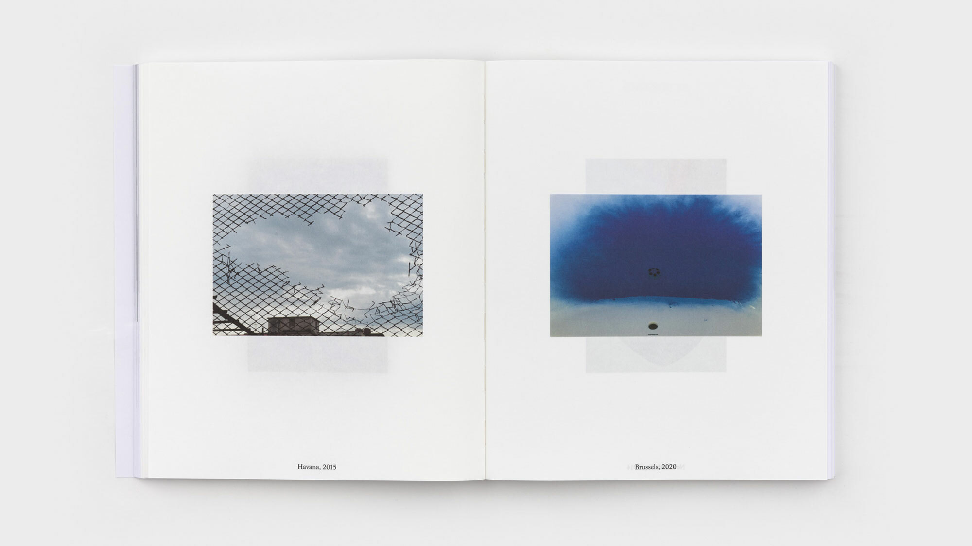 A spread bearing two, small rectangular photographs entombed in generous white space. Verso is an image captured in Havana in 2015 through an eroded fence. Recto stands a sink at the bottom of which is a pool of Klein-blue powder.
