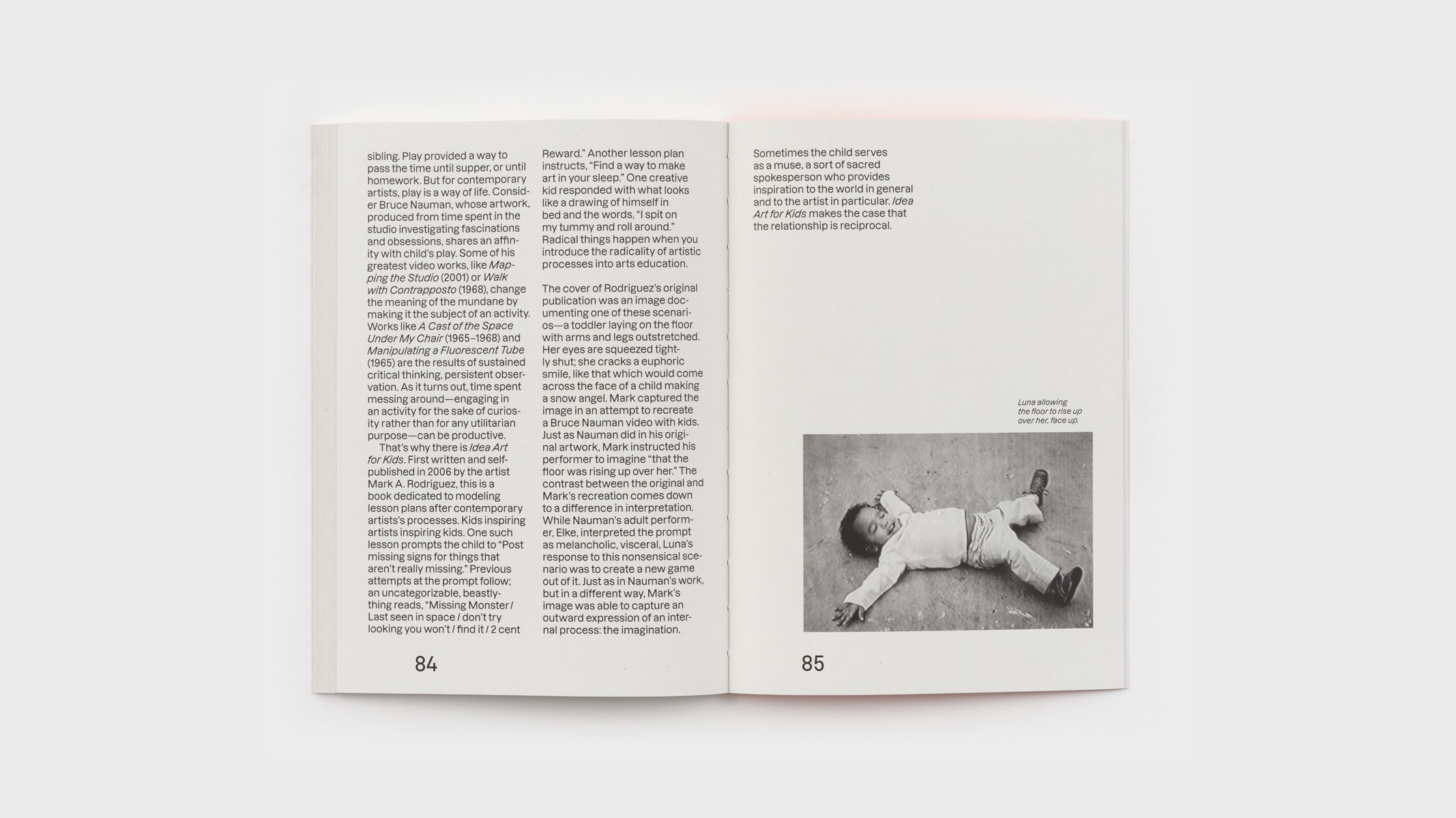 Two pages of Lola Kramer's essay on play, idea art, and children. Like Mark's introduction, it runs across two columns. On the right page is a black and white image of a young girl, Luna, prone on the ground like a snow angel.